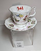 Teacup stacked on saucer showing floral pattern and Canadian flag motif