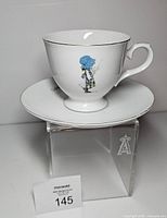 Teacup on saucer showing Holly Hobbie figure and silver trim