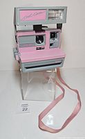 Front view showing lens, flash, branding, pink and gray colourway, strap visible