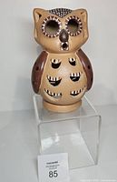 Front view of ceramic owl lantern showing cut-outs and paint