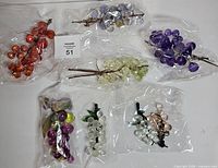 Seven bagged grape clusters assorted colours on white background