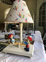 Raggedy Ann and Andy lamp with music box base, showing chipped paint and colorful patterned lampshade.