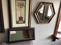 Full view of the palm tree print in rectangular frame alongside the hexagon-shaped mirror and the rectangular mirror on a sofa back.
