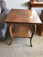 Front view of the vintage natural wood parlor table showing the table top and elegantly curved legs with the shelf underneath.