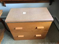 Front view of wooden 2 drawer file cabinet with upholstered tan faux ostrich leather top with nail head trim