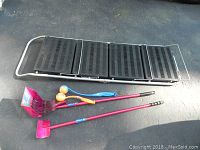 Folding dog ramp in step form with pet scoop set and Chuckit ball launchers placed on asphalt surface