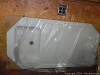 Photo of the white plastic tabletop with integrated sink basin covered in clear plastic wrapping.