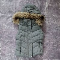 Front view of grey hooded vest with faux fur trim