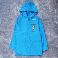 Front view of blue vinyl raincoat showing hood, pockets, Pee-wee Herman graphic