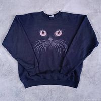 Full view of black crewneck sweatshirt showing cat face graphic