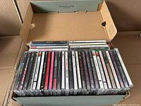 Shoebox holding approximately 35 jewel-cased CDs