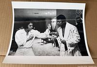 Front view of black & white photographic print showing two men in sparring pose