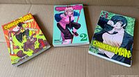 Front covers of volumes 1-3 laid out on cardboard