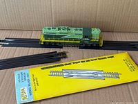 Locomotive on black track pieces with yellow Atlas track packaging visible