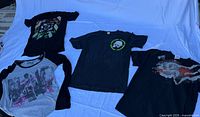 Front view of all four T-shirts laid flat showing graphics and styles