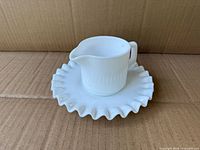 Creamer resting on hobnail ruffled saucer
