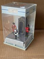 Full diorama in clear case showing three figures and backdrop
