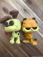 Front view of Garfield and Odie vinyl figures standing on wooden surface