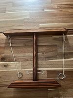 Front view of wooden stand showing cords, rings and hooks