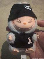 Front view showing gray plush figure, vinyl face, black beanie, black LABUBU shirt