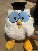 front view of white plush owl with cap