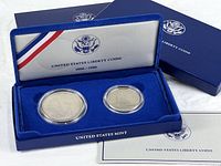 Presentation case open with both encapsulated coins, outer box and certificate visible