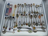 Top tray view showing first group of souvenir spoons with enamel crests and boxed pair