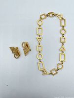 Necklace laid flat beside both earrings showing geometric shapes