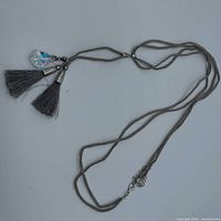 Full view of multi-strand grey suede lariat necklace with tassels and crystal accent