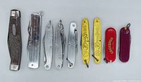 All nine knives and multi-tools lined up left to right for full inventory view