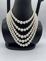 Front view showing five cascading strands of graduated faux pearls on display bust