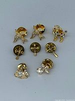 Group shot of all eight gold-tone lapel pins and tie tacs with backs