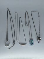 All five necklaces laid out showing pendants and chain styles