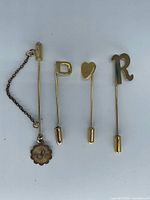 All four stick pins laid out to show shapes, chain and charm