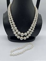 Front view showing two-strand graduated faux pearl necklace on display and detached strand