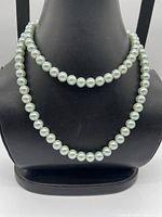 Necklace displayed on bust showing uniform light green faux pearls