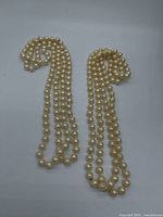 Two cream pearl strand necklaces laid flat