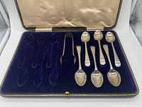 Open presentation case showing five teaspoons and sugar tongs