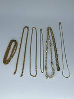 All six gold-tone chains laid out flat