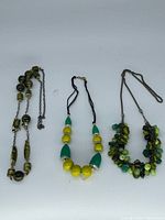 Three necklaces laid flat showing overall styles and colours