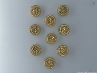 Nine matching gold-tone button covers arranged on flat surface
