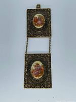 Full view of two-panel hanging plaque showing metal frames, chain connector and porcelain scenes