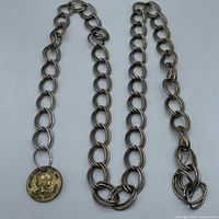 Full view of metal chain belt showing alternating link sizes and attached coin pendant