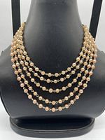 Front view showing five strands of faux pearls on display bust