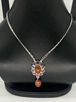 Front view of necklace on bust showing pendant, chain, crystals, and resin elements
