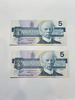 Obverse of both $5 notes showing Sir Wilfrid Laurier and serial numbers