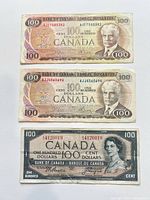 Obverse of three $100 Canadian banknotes showing portraits, colours and serial numbers
