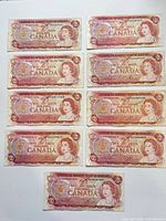 Obverse view of all nine 1974 $2 notes showing portraits, serial numbers and overall wear