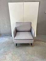 Front view of grey lounge chair showing upholstery and legs