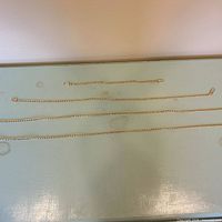 All four gold-tone chains laid out to show relative lengths